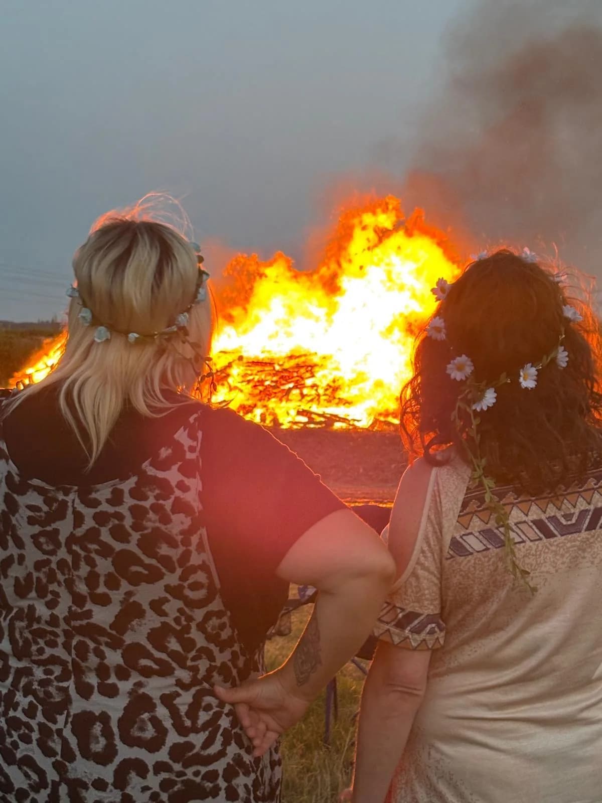 Two friends with flowers in their hair enjoying the Merry Farm campfire